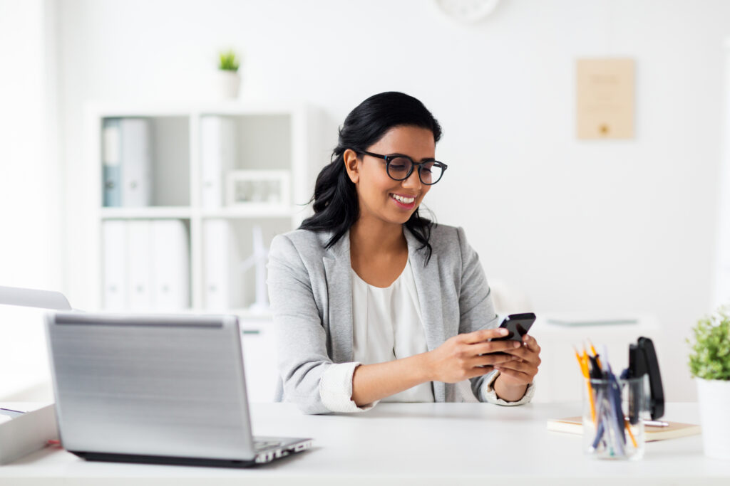 Smart businesswoman holding a smartphone used to send texts on behalf of her business