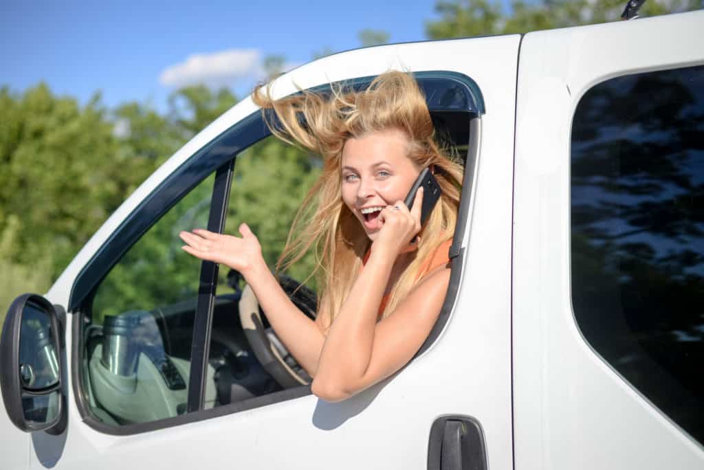 Blond driver using phone hanging out of the van window without worrying her burner phone number can be traced