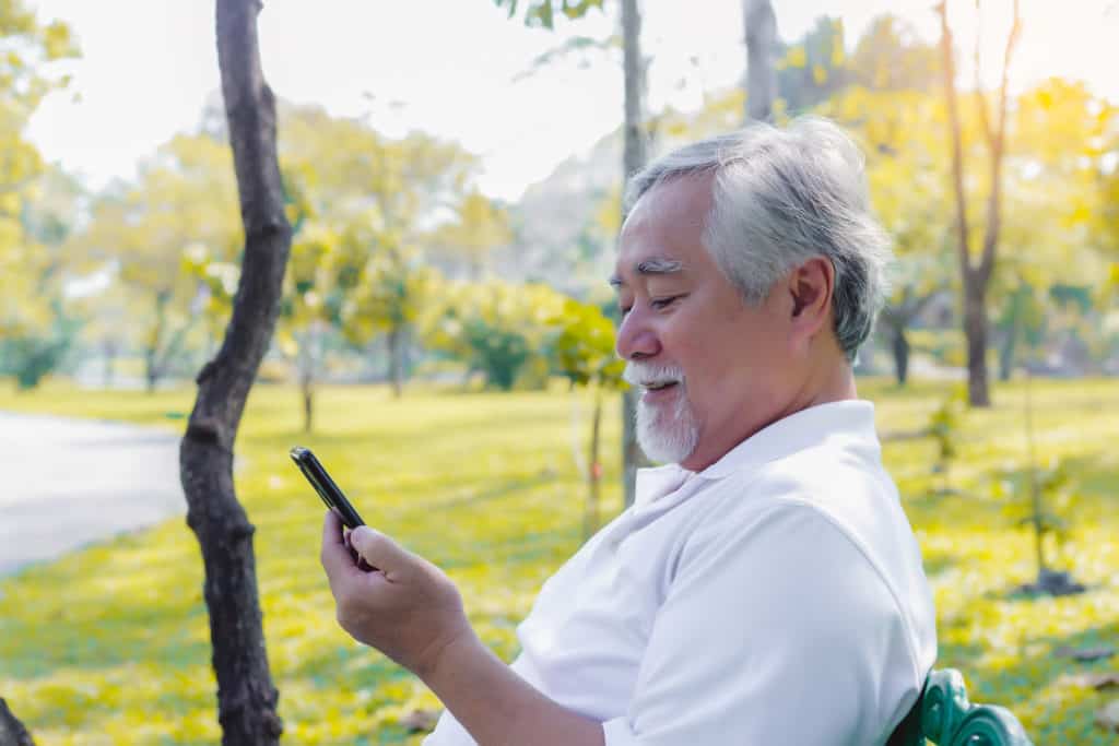 Older man in a park using his burner phone number so he can't be traced