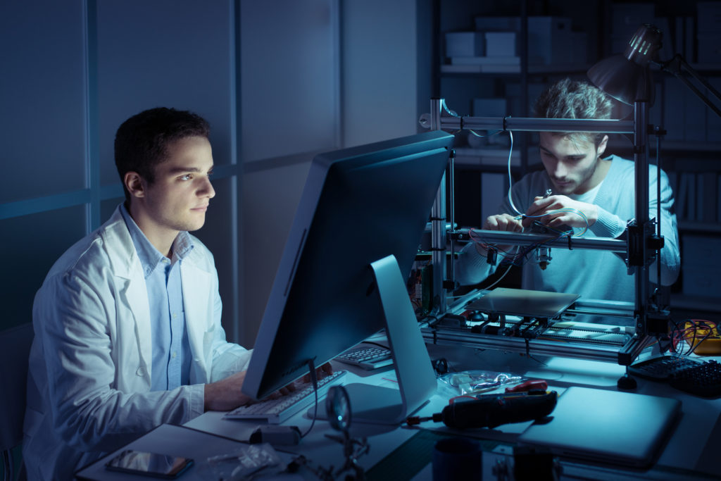 Two males, one a computer engineer the other a computer scientist working together in a dark lab.