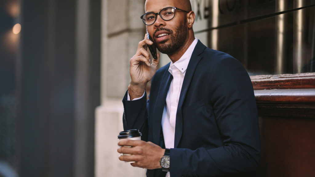 Business man in suit on expensive smartphone outside office building.