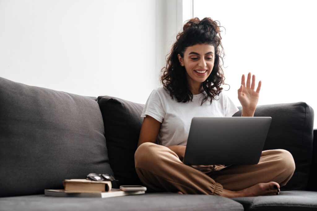 Happy brunette woman waing hand while talking on a call using latop
