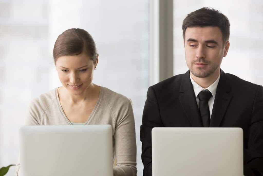 Business man looking over his colleague's laptop to see her Google Drive files