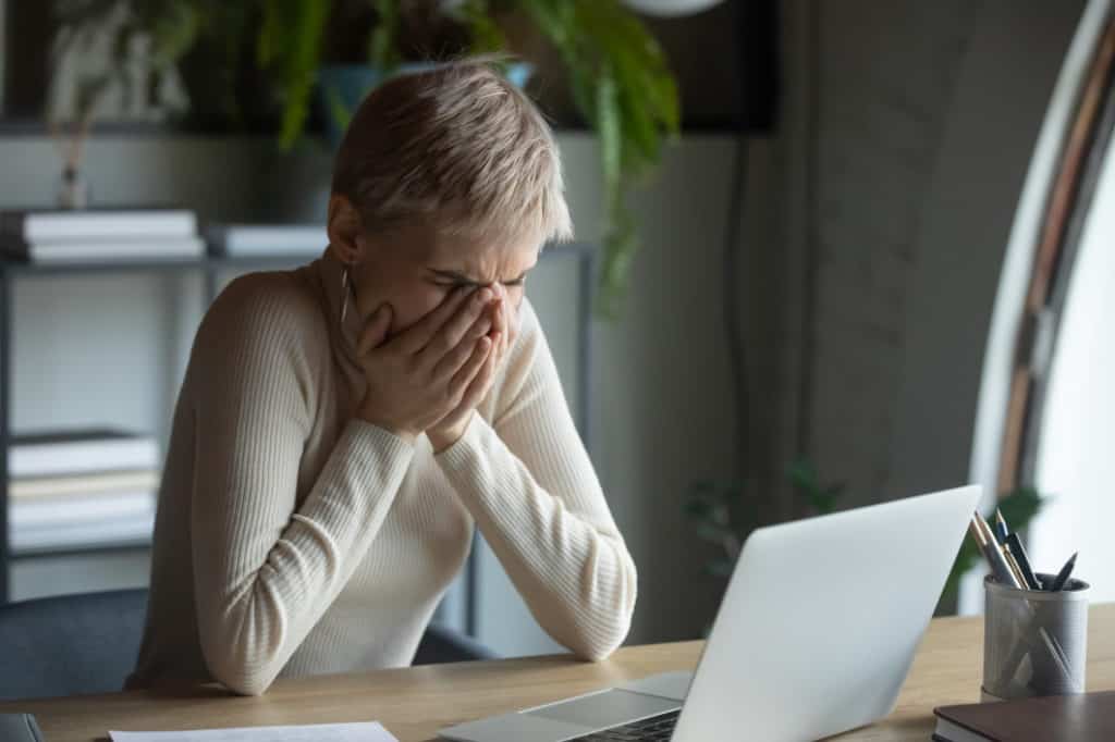 Woman with laptop covering her mouth after accidentally opened a spam email