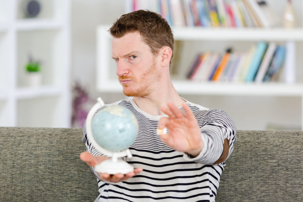Man holding a globe and SIM chip with questioning look wondering if you can use a phone without a SIM card