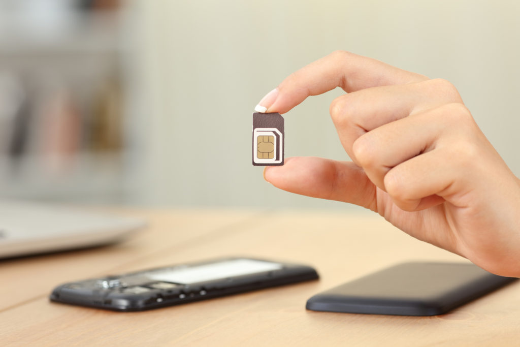 Woman's hand holding a SIM chip leaving her to wonder if you can use a phone without a SIM card