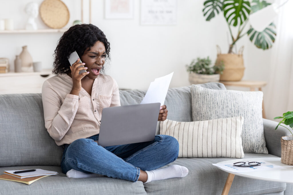 Angry woman looking at cell phone bill because her phone might have been hacked