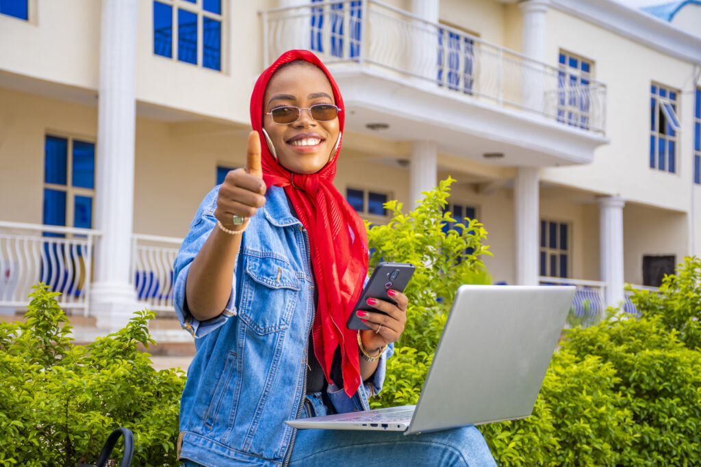 Woman sitting with her laptop giving a thumbs up now that her hacked phone is fixed