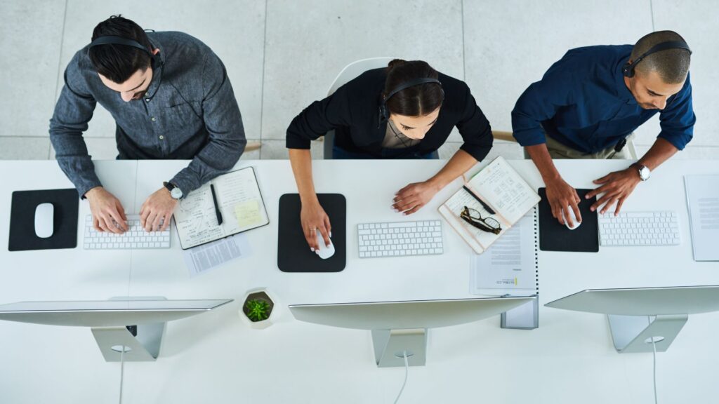 three help desk professionals, one woman and two men, taking notes as they troubleshoot customers' problems